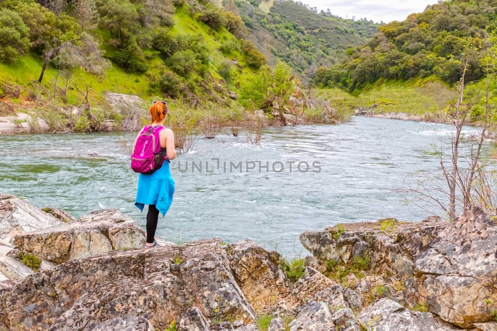 Young Girl Standing on Rocks Near Fast River