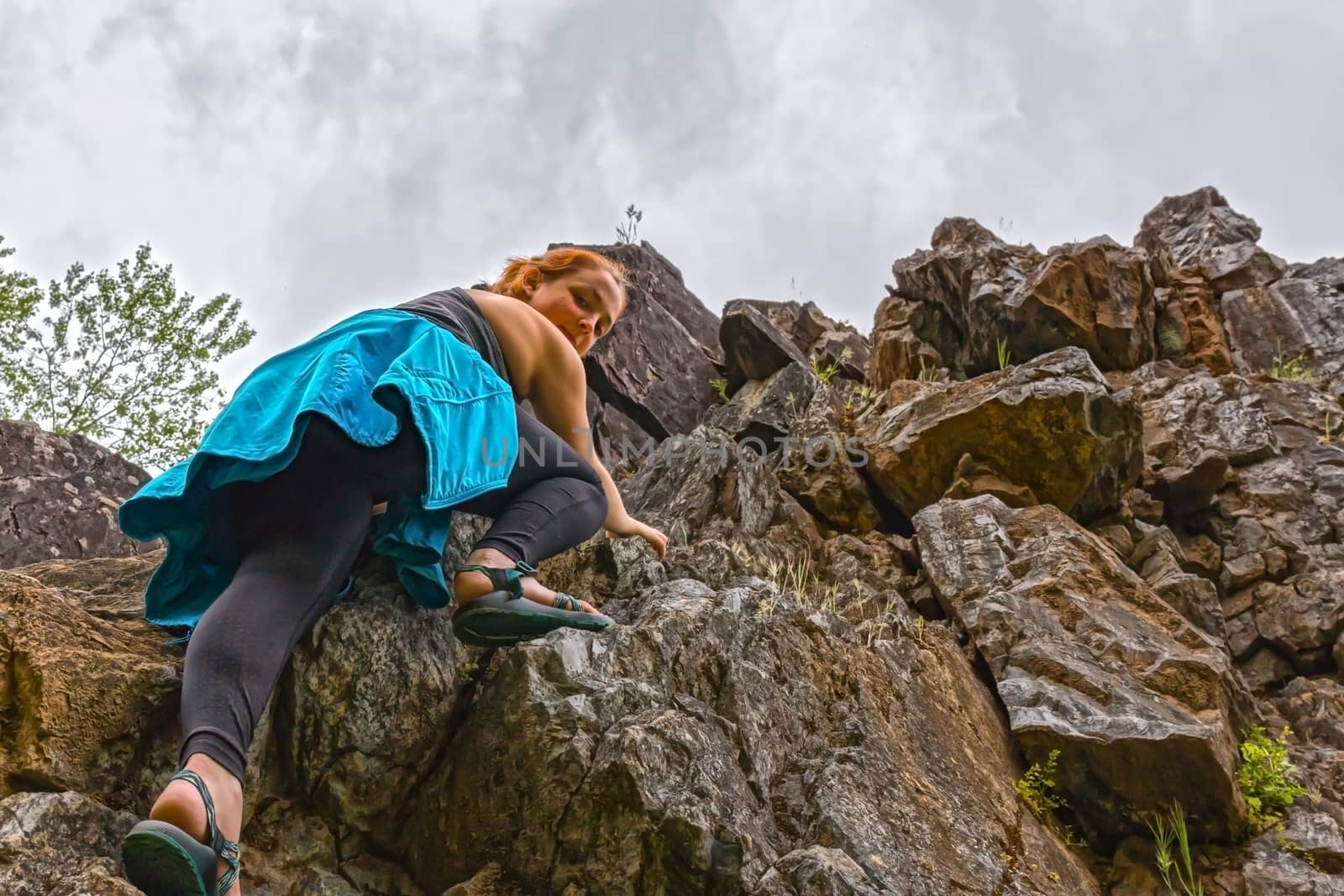Girl Climbing up Rocks Looking Down by gregorydean