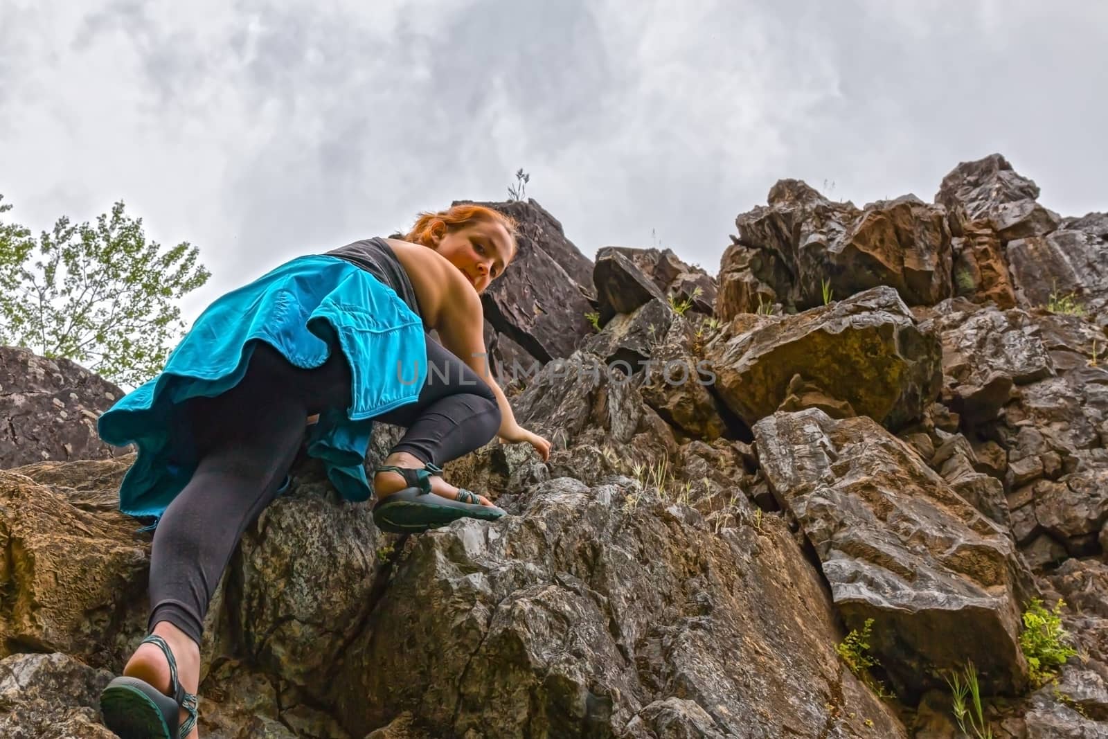 Young Girl Climbing up Rocks and Looking Down