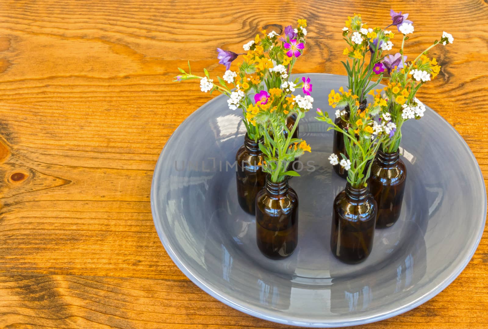 Gray Plate With Small Vases With Flowers Sitting on Wooden Table