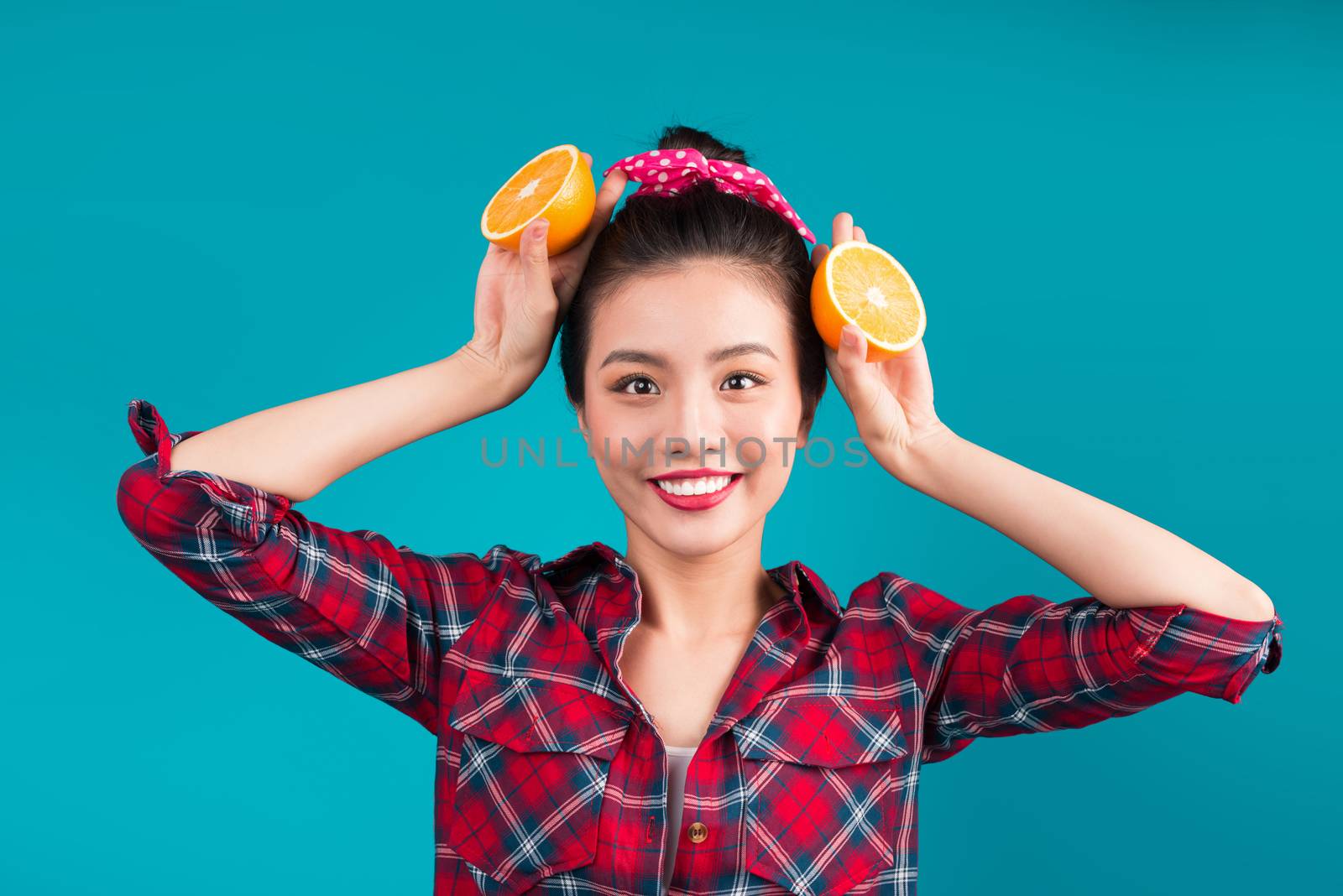 Healthy food. Smiling lovely pinup asian girl holding orange ove by makidotvn