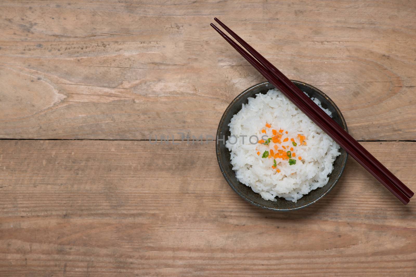 Boiled rice in a bowl on wooden table.