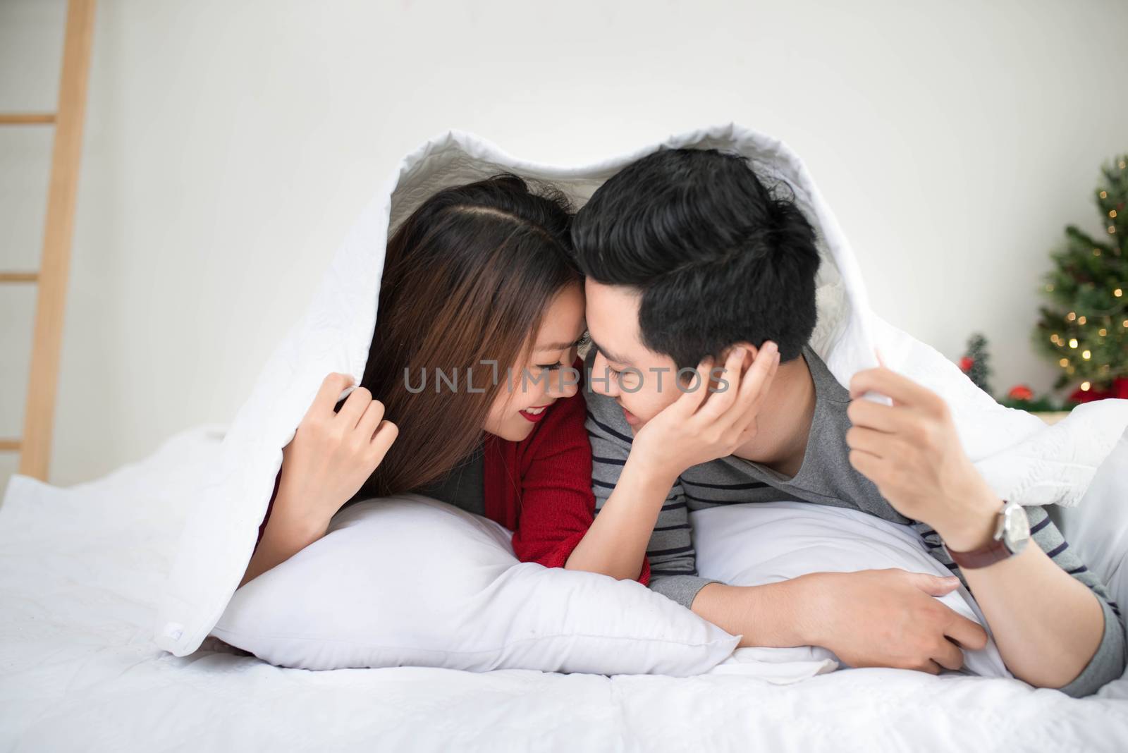 Couple in love sharing genuine emotions and happiness lying on bed.