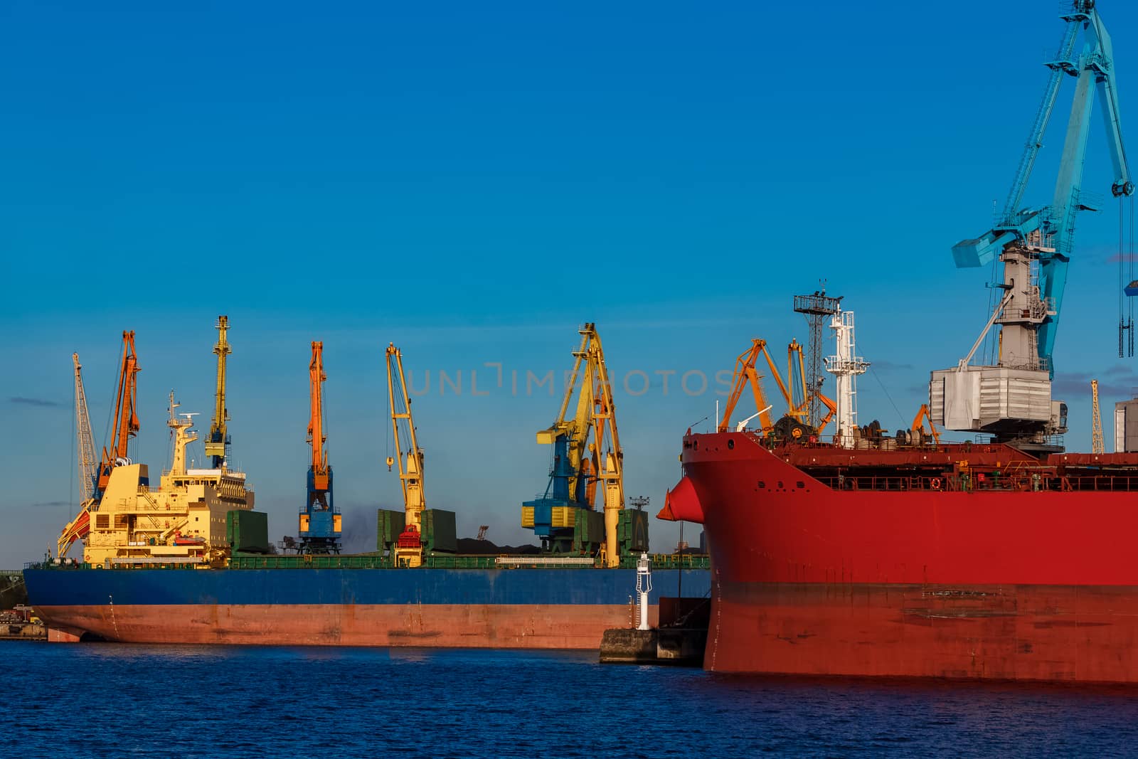 Red and blue cargo ship loading in the port of Riga