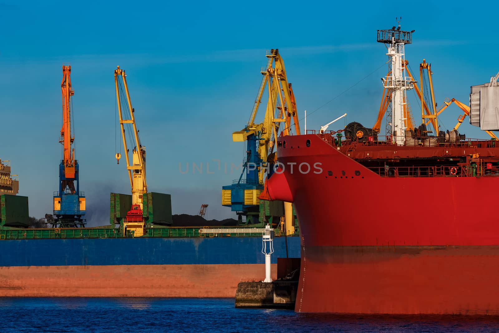 Red and blue cargo ship loading in the port of Riga