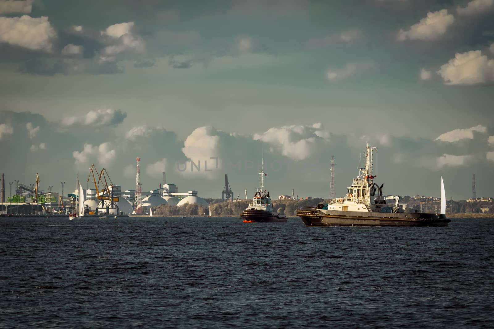 Two tug ships are accepting cargo vessel at Daugava river