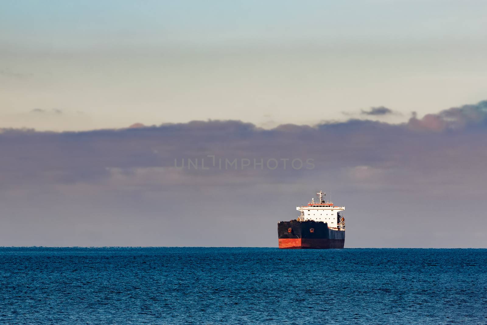 Black cargo ship moving in still Baltic sea water. Riga, Europe