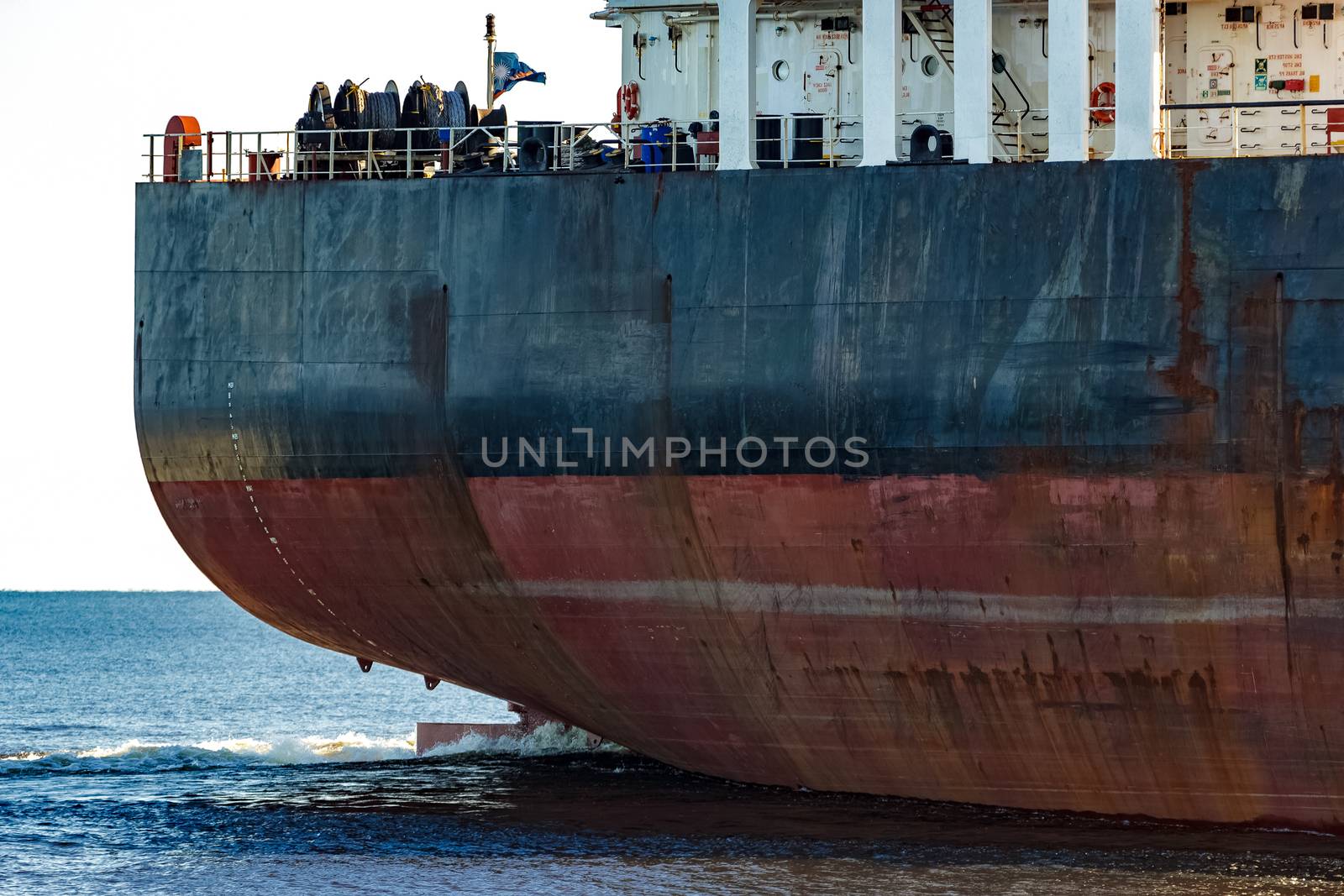 Black cargo ship's stern in still water close up. Riga, Europe