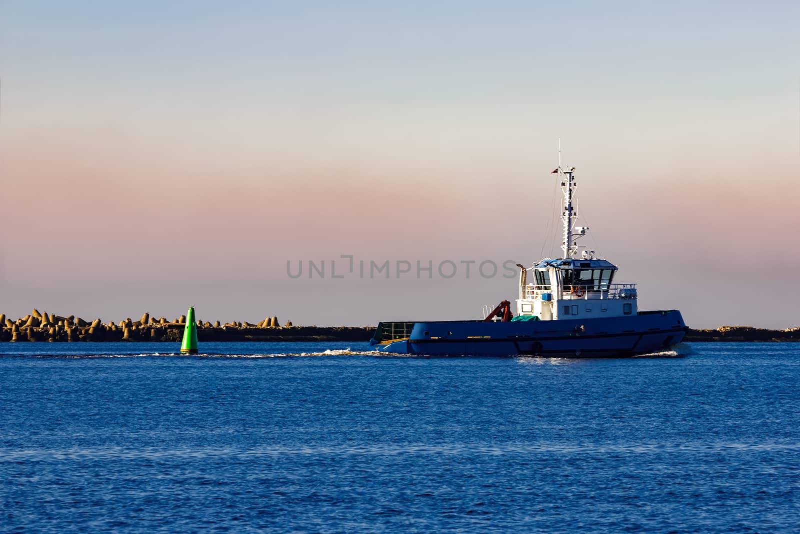 Blue small tug ship leaving Riga and entering the Baltic sea