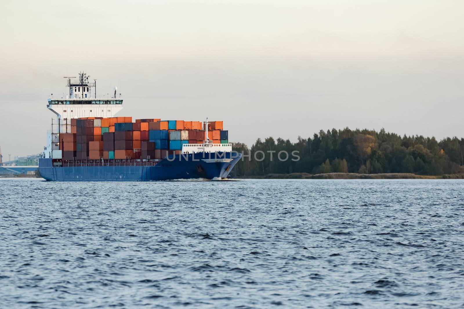 Blue container ship moving to Baltic sea. Riga, Latvia