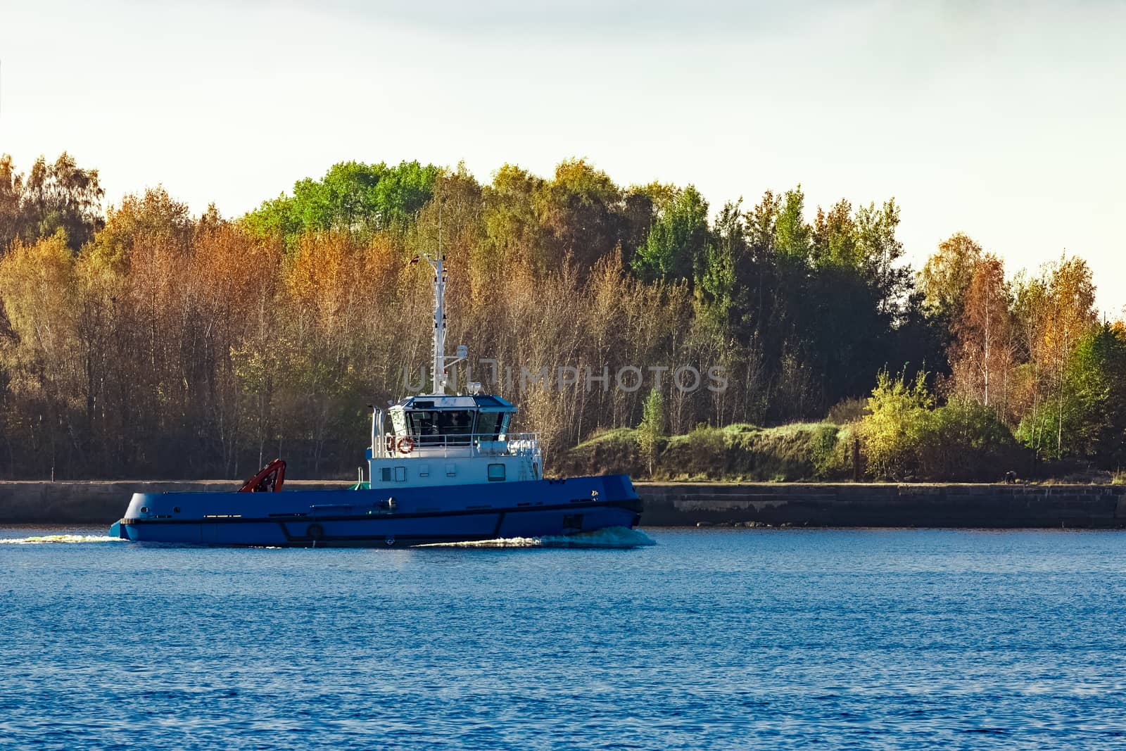 Blue small tug ship leaving Riga and entering the Baltic sea