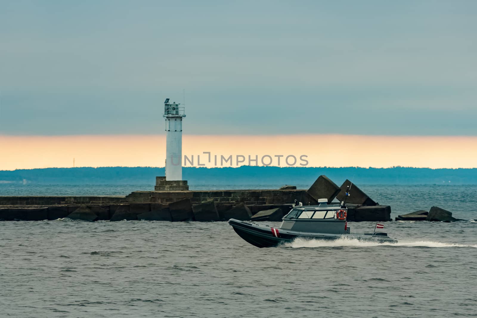 Small grey border guard boat moving fast in still evening