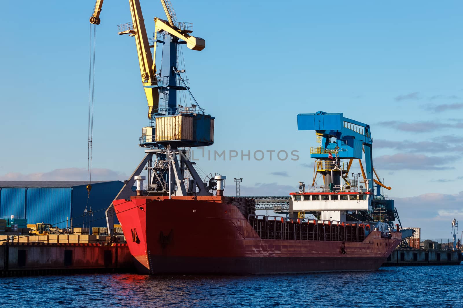 Red cargo ship loading in the port of Riga, Europe