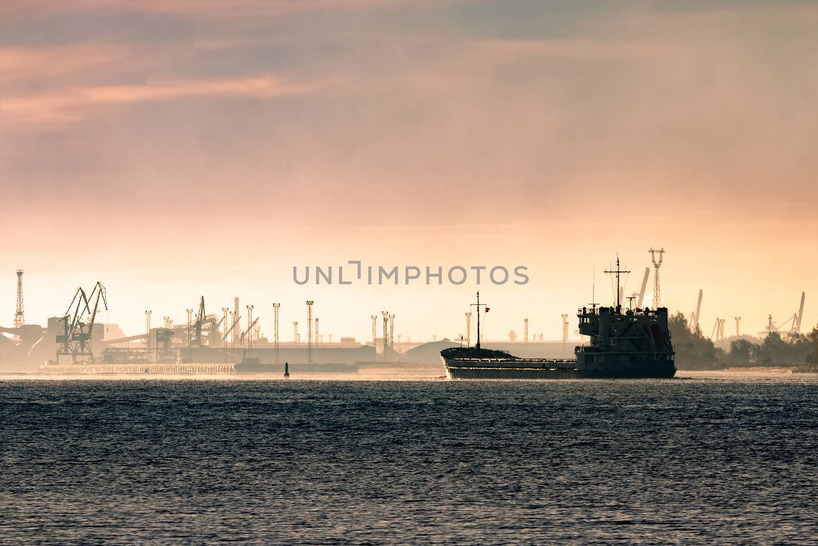 Cargo ship silhouette entering a port of Riga at the morning