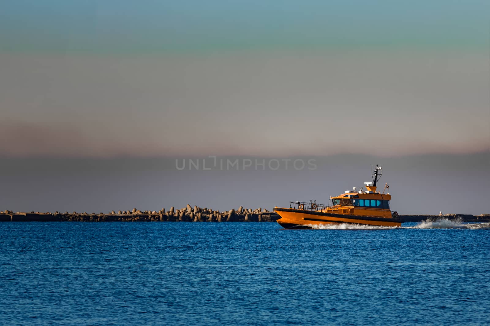 Orange pilot ship sailing from the Baltic sea in Latvia