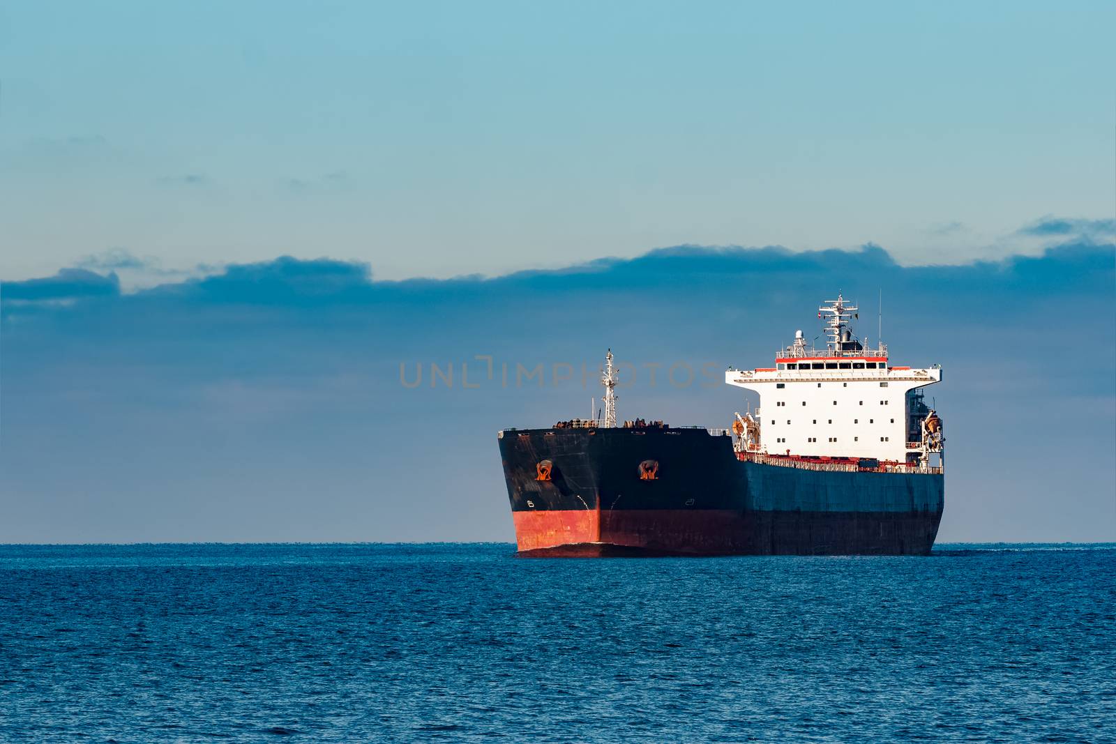 Black cargo ship moving in still Baltic sea water. Riga, Europe