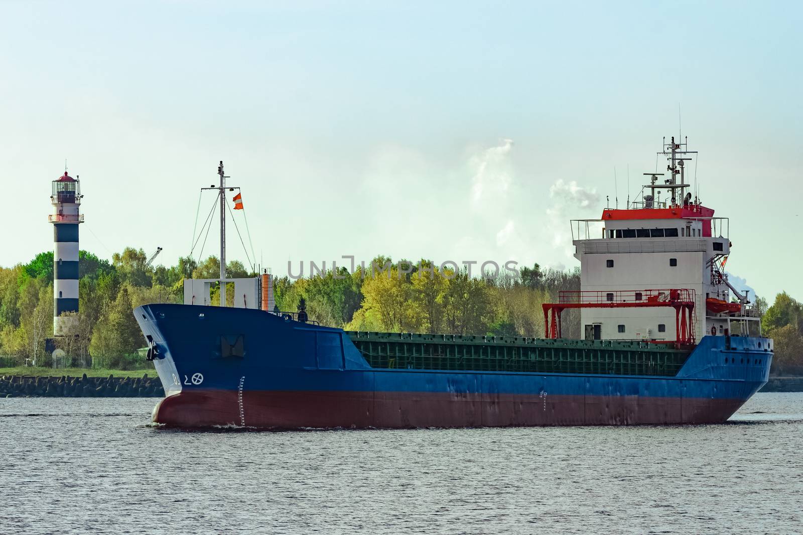 Blue cargo ship leaving the port of Riga at sunny day