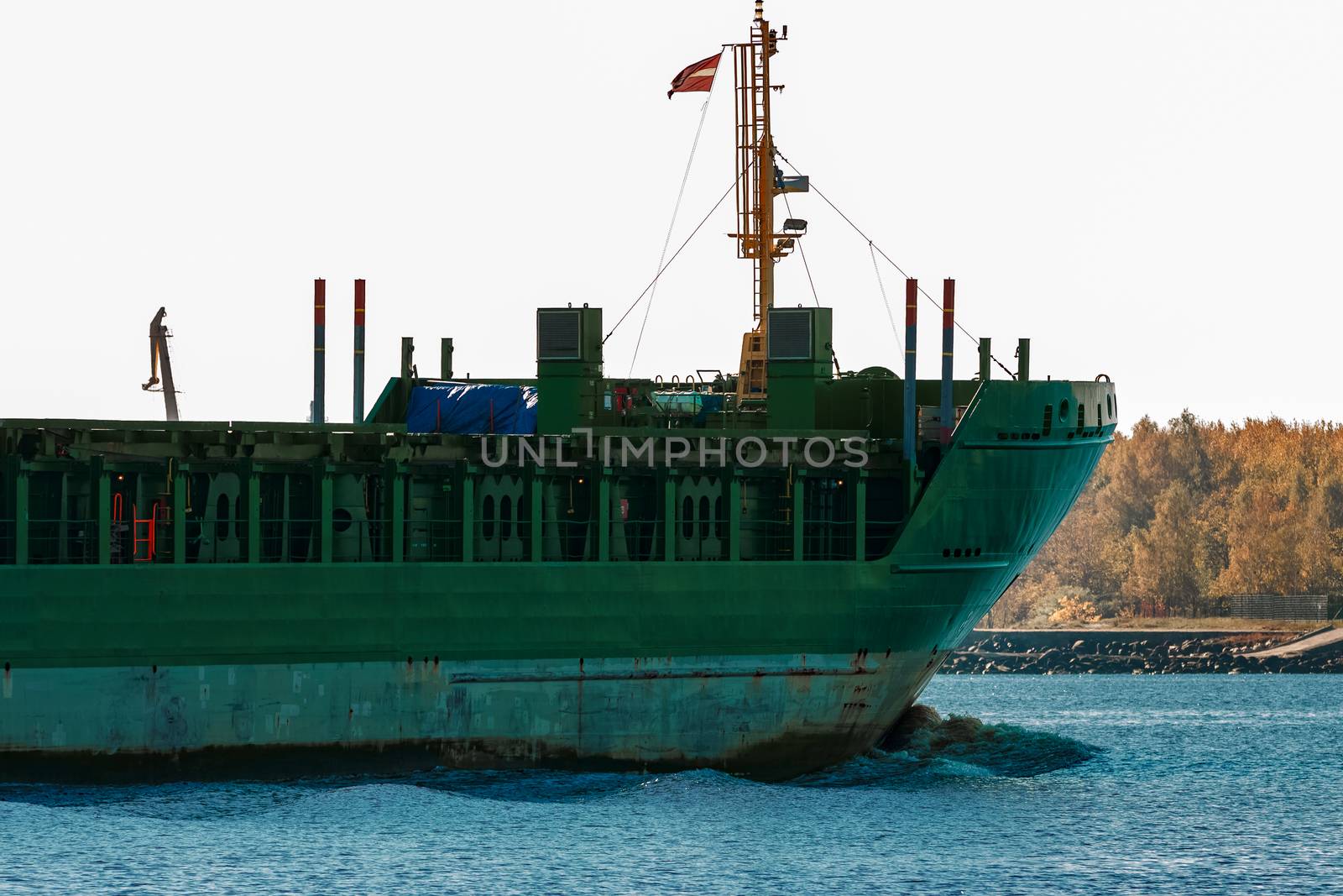 Green cargo ship's bow close up in still water, Riga