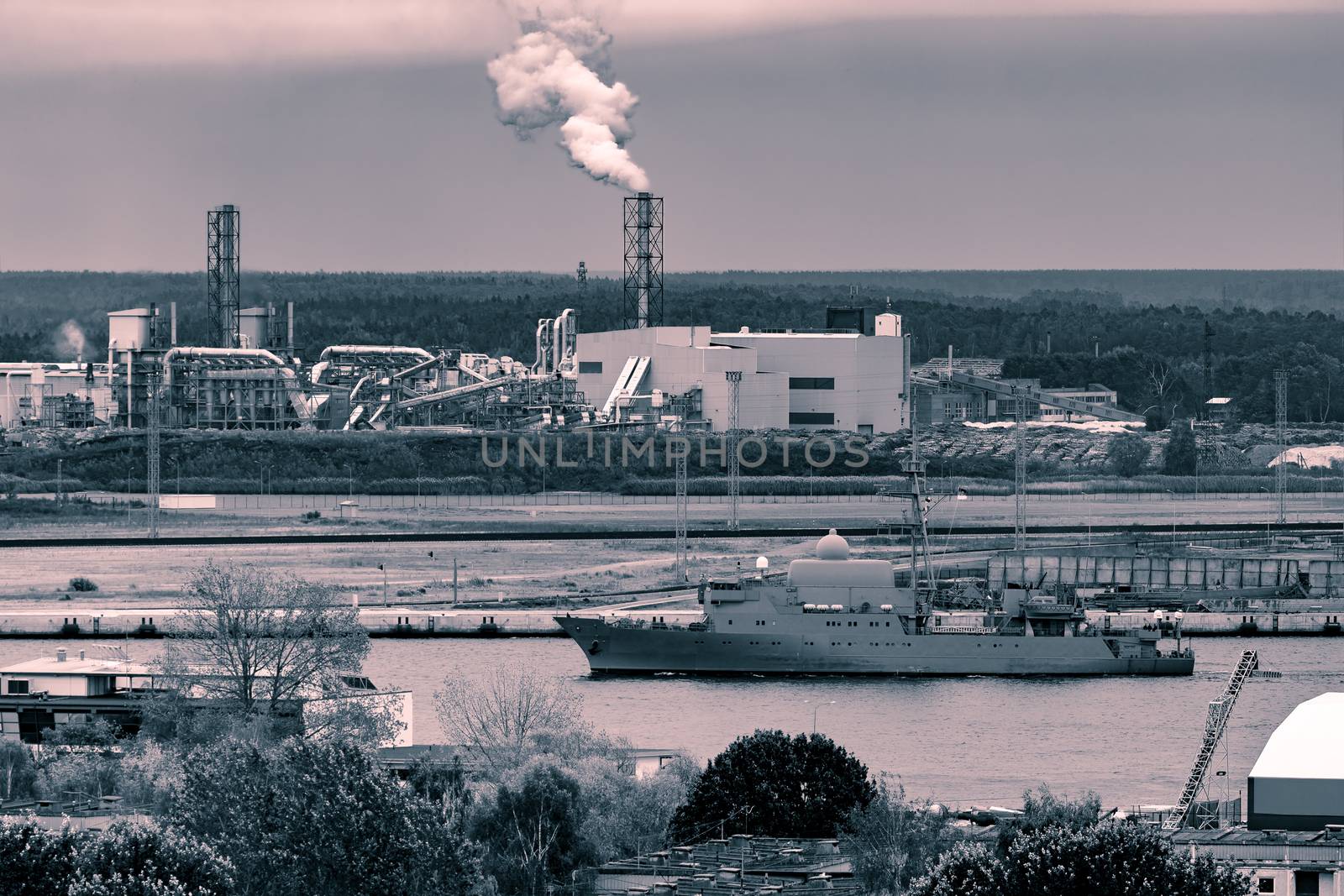 Military ship sailing past the cargo port in Riga, Latvia