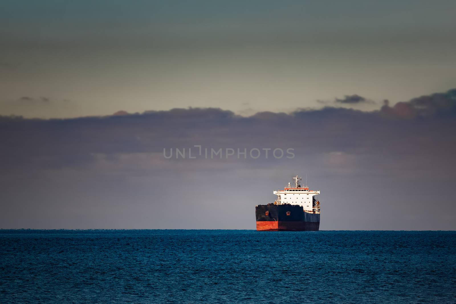 Black cargo ship moving in still Baltic sea water. Riga, Europe