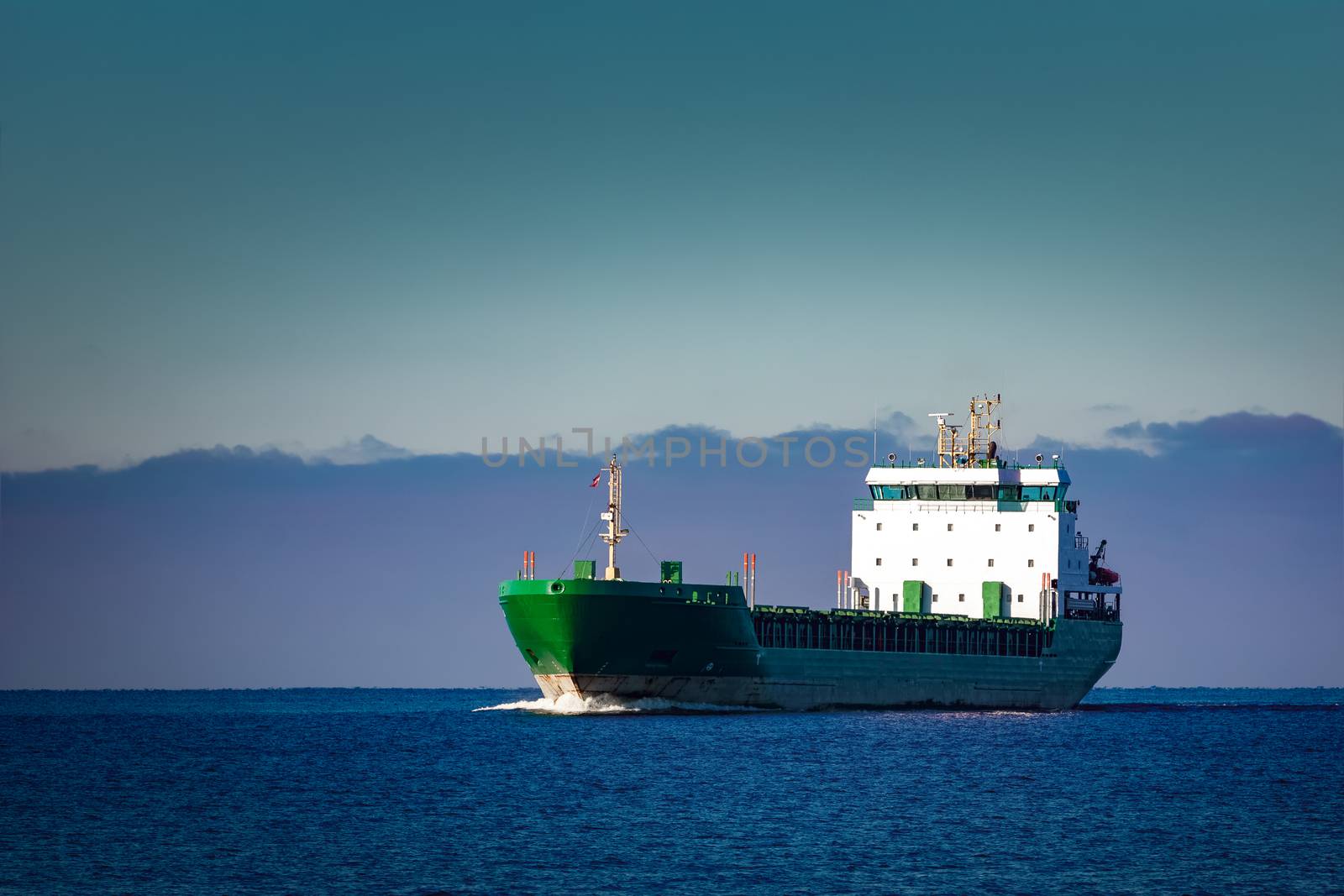 Green cargo ship moving in still water of Baltic sea