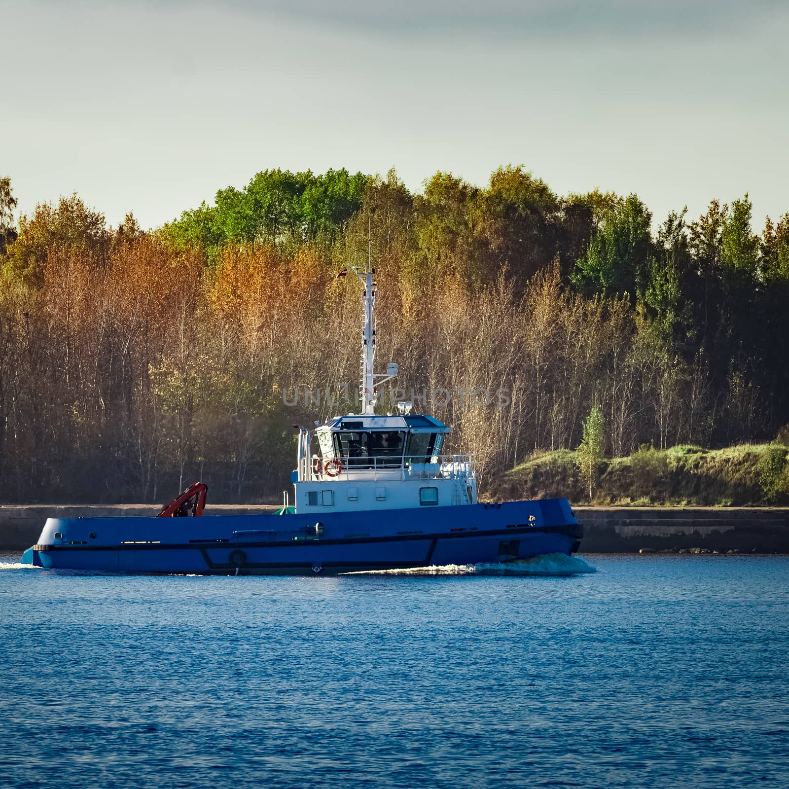 Blue small tug ship leaving Riga and entering the Baltic sea