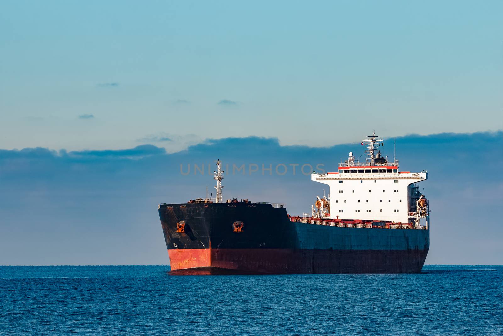 Black cargo ship moving in still Baltic sea water. Riga, Europe