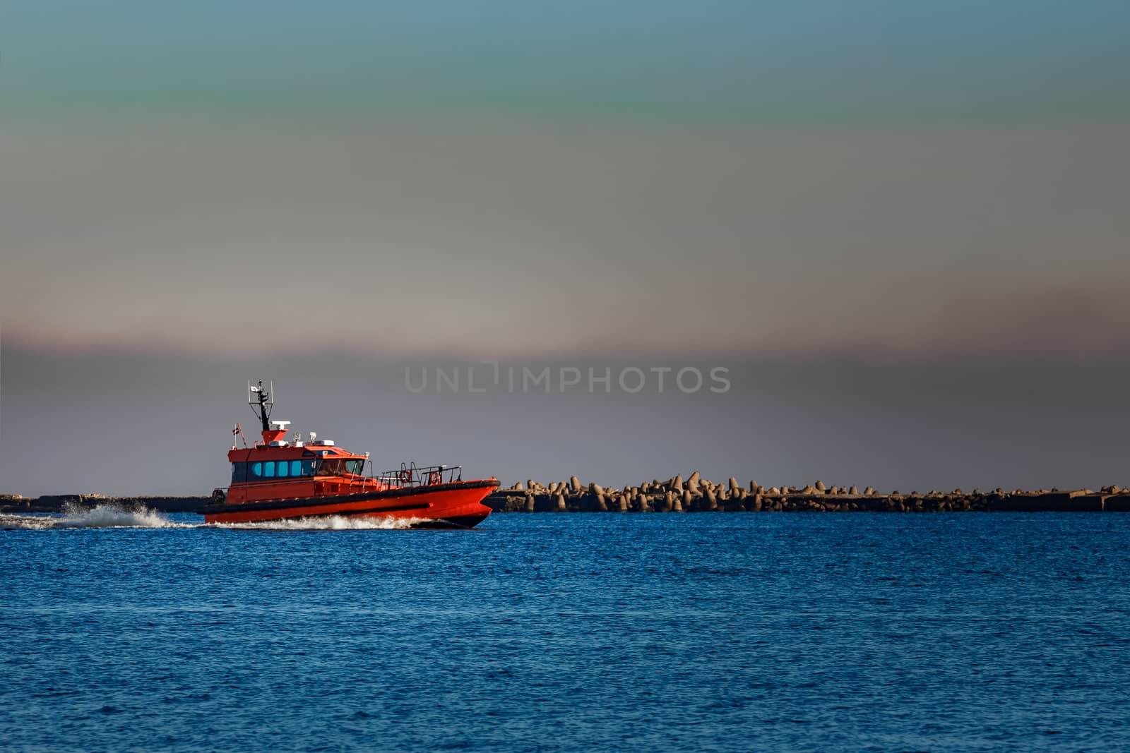 Red pilot ship moving past the breakwater dam in Riga, Europe