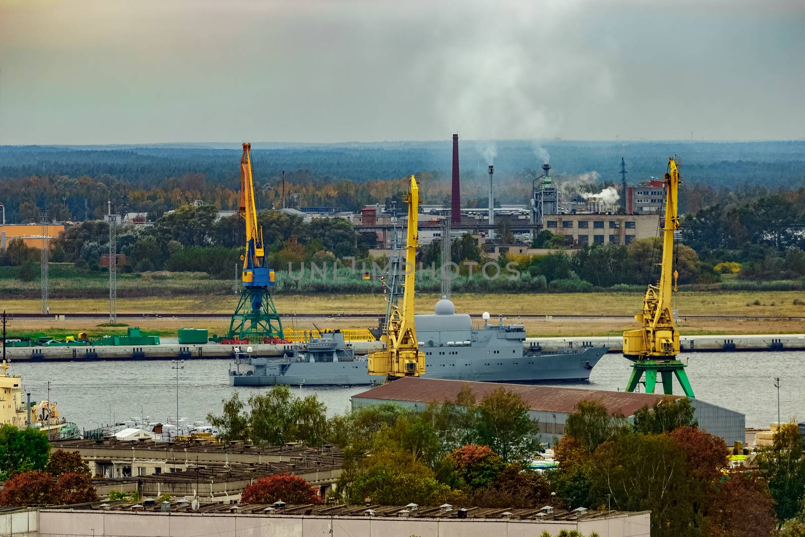 Military ship sailing past the cargo port in Riga, Latvia