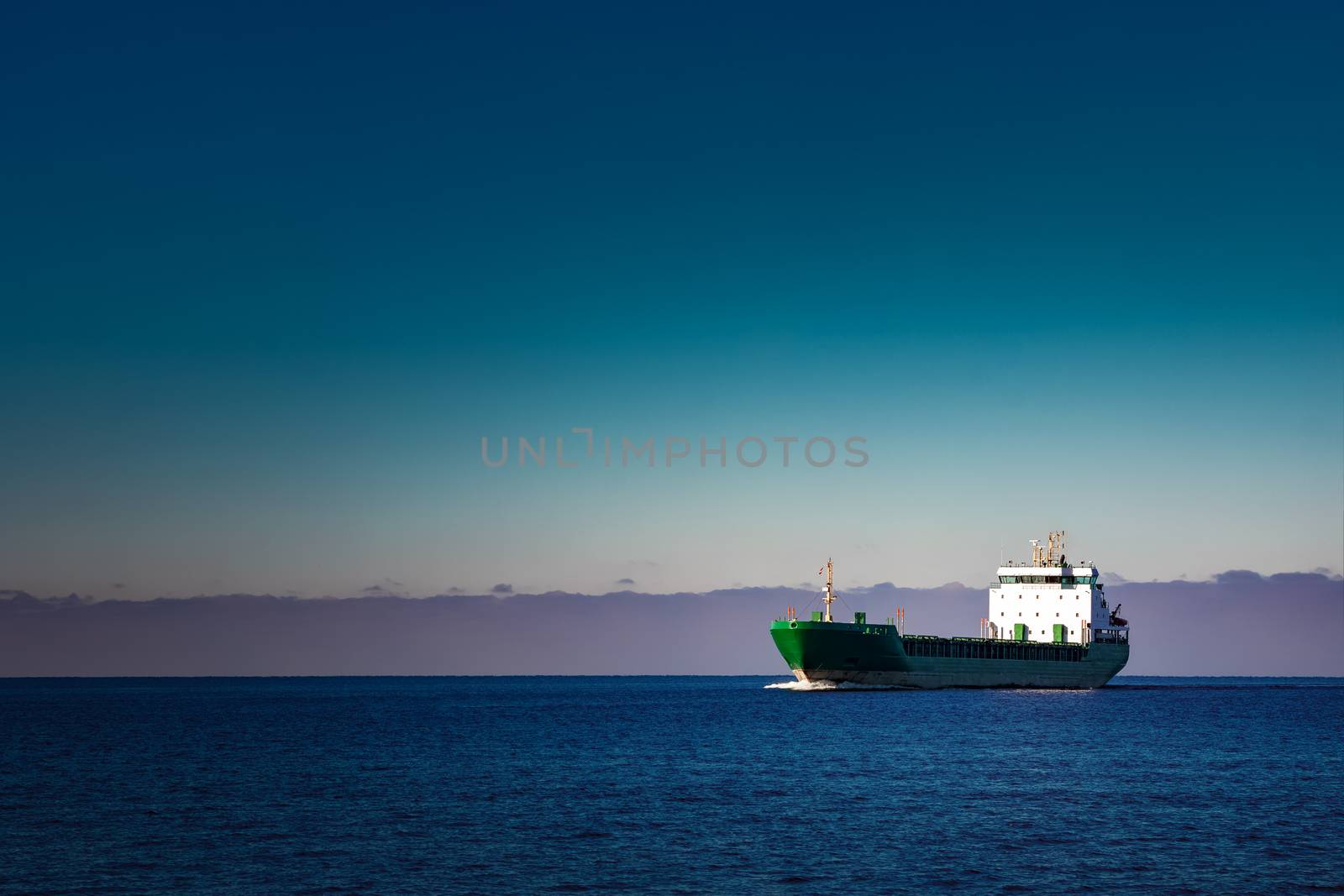 Green cargo ship moving in still water of Baltic sea