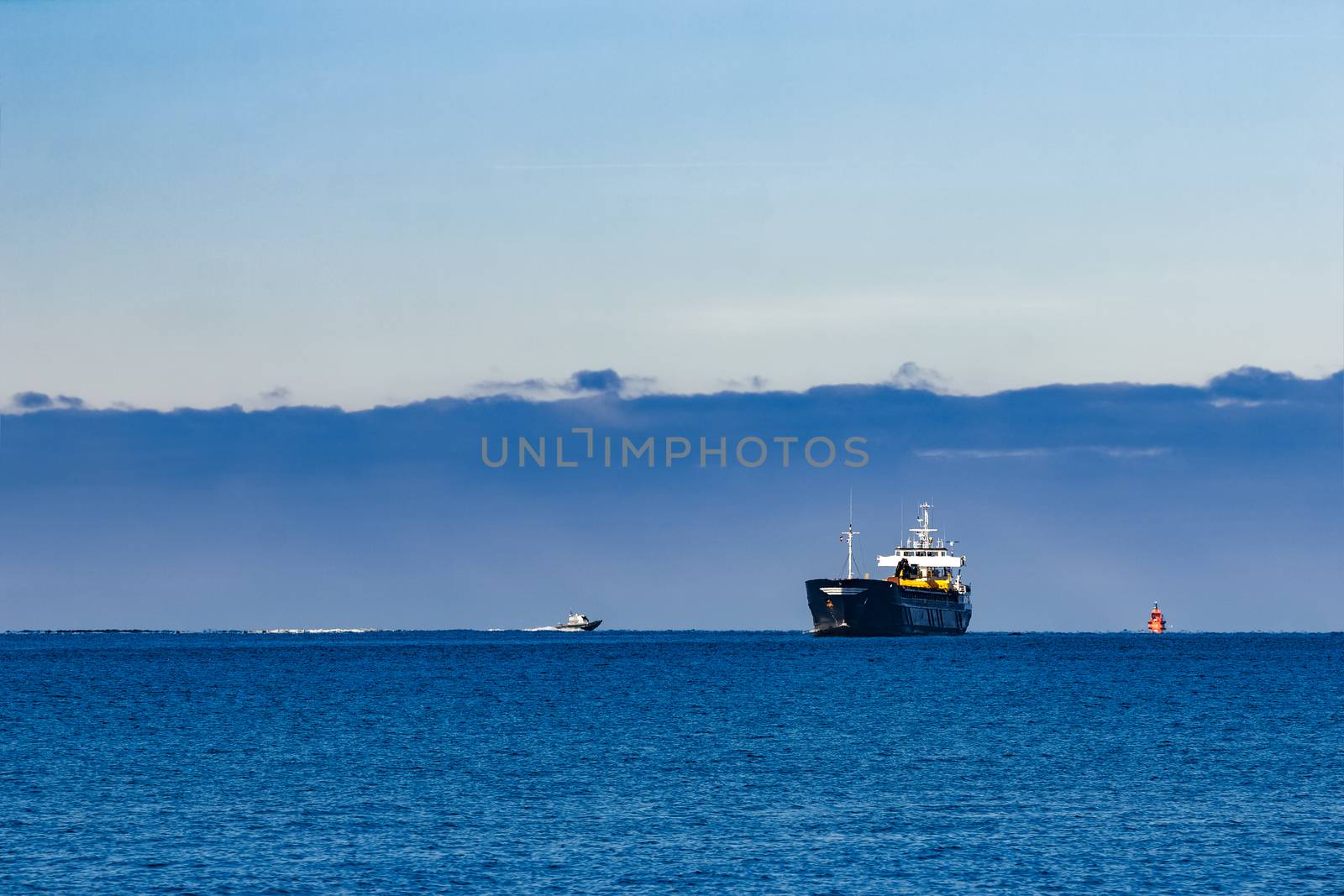 Black cargo ship with long reach excavator moving by baltic sea