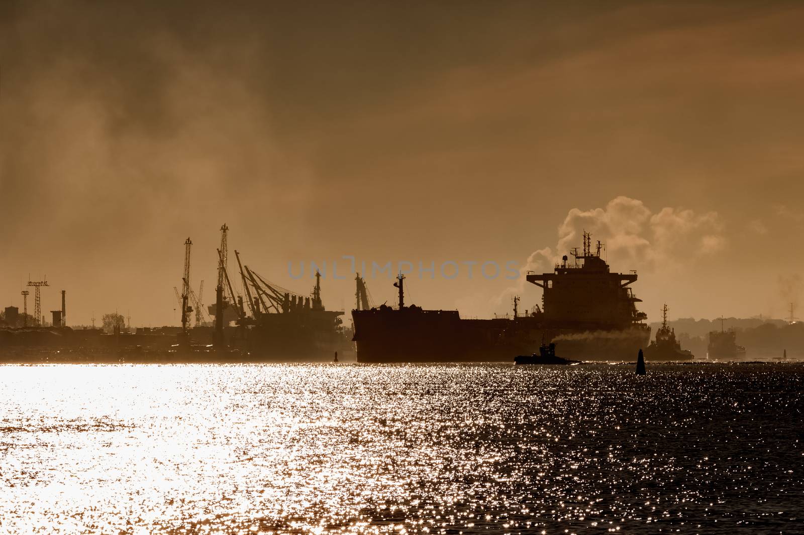 Cargo ship silhouette entering a port of Riga at the morning