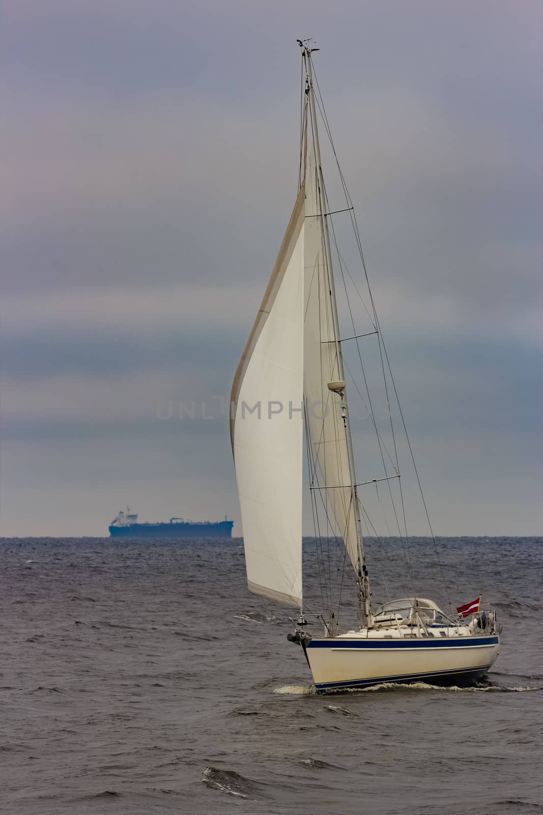 White sailboat traveling in Baltic sea in cloudy day