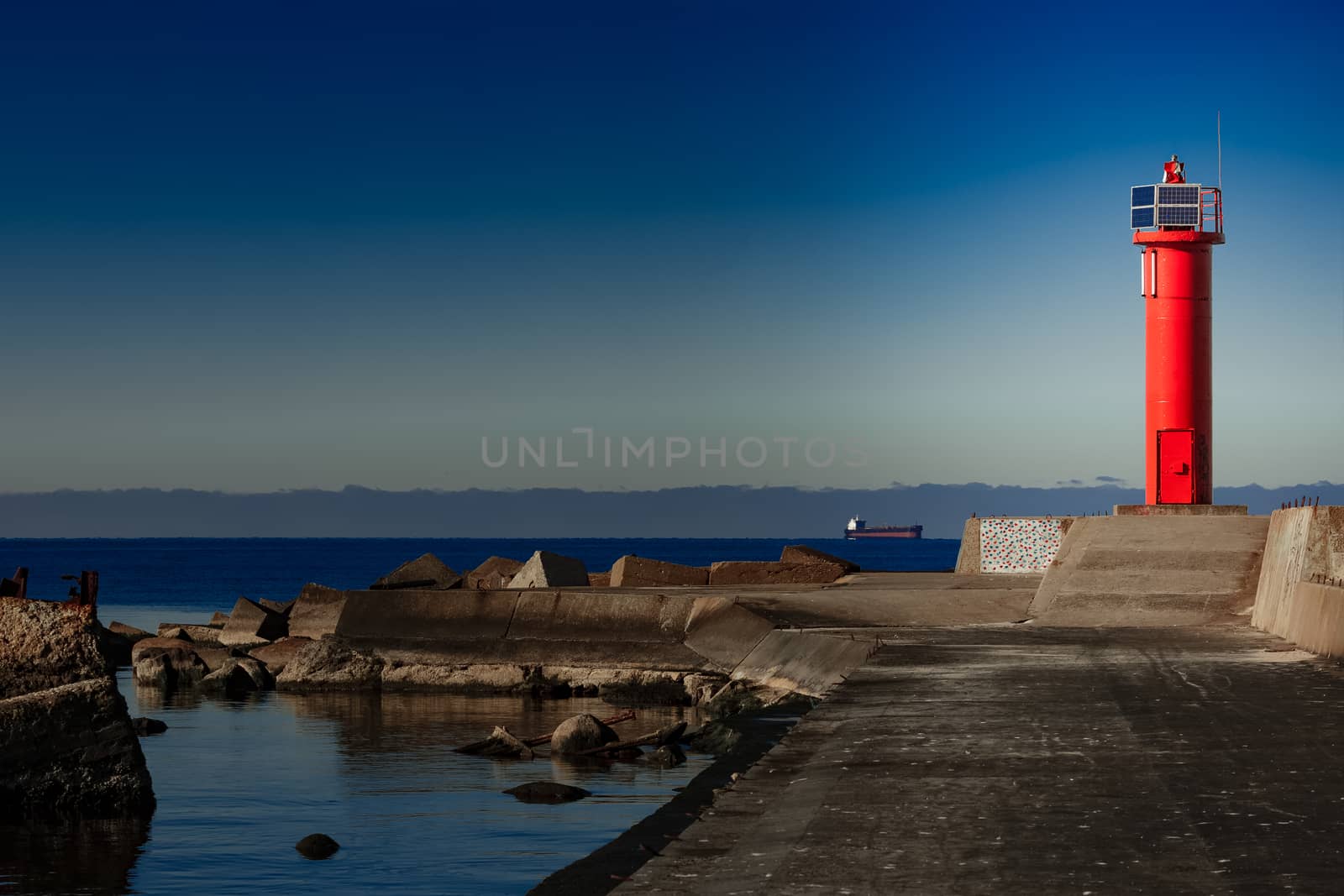 Red lighthouse on breakwater dam by sengnsp