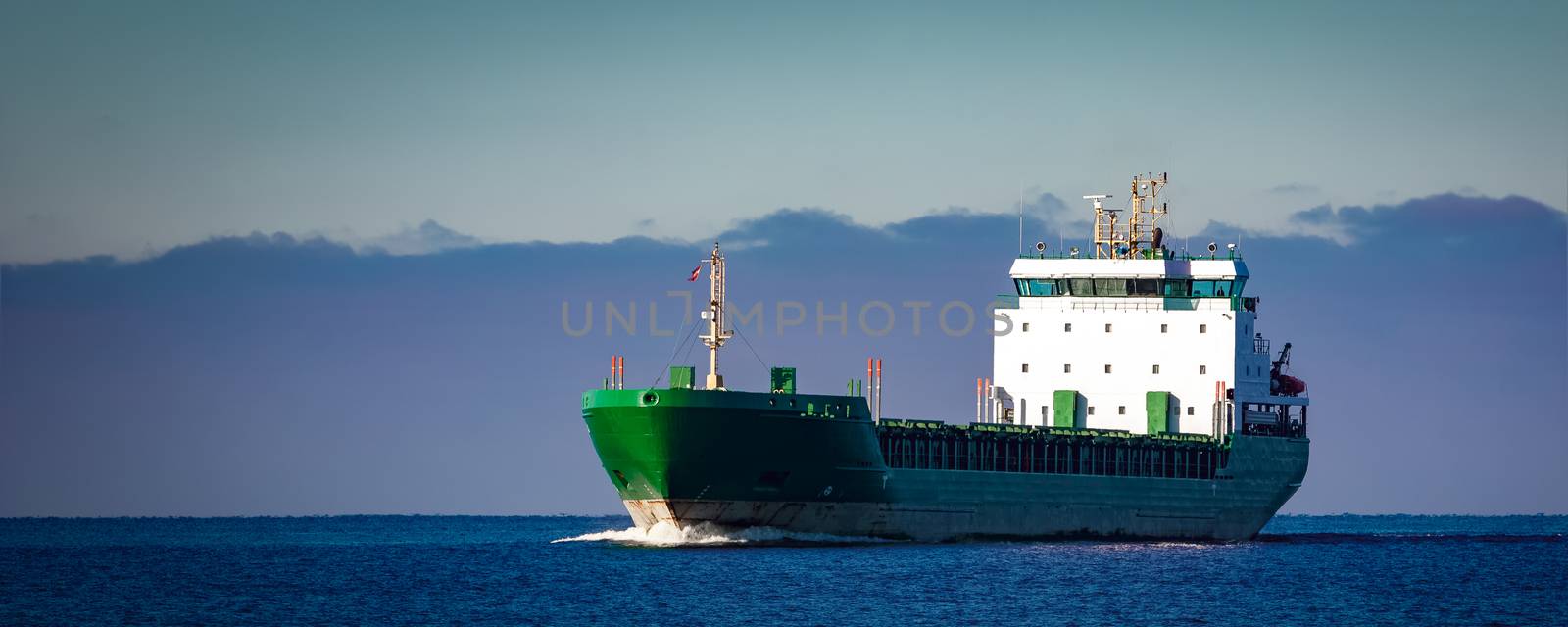 Green cargo ship moving in still water of Baltic sea