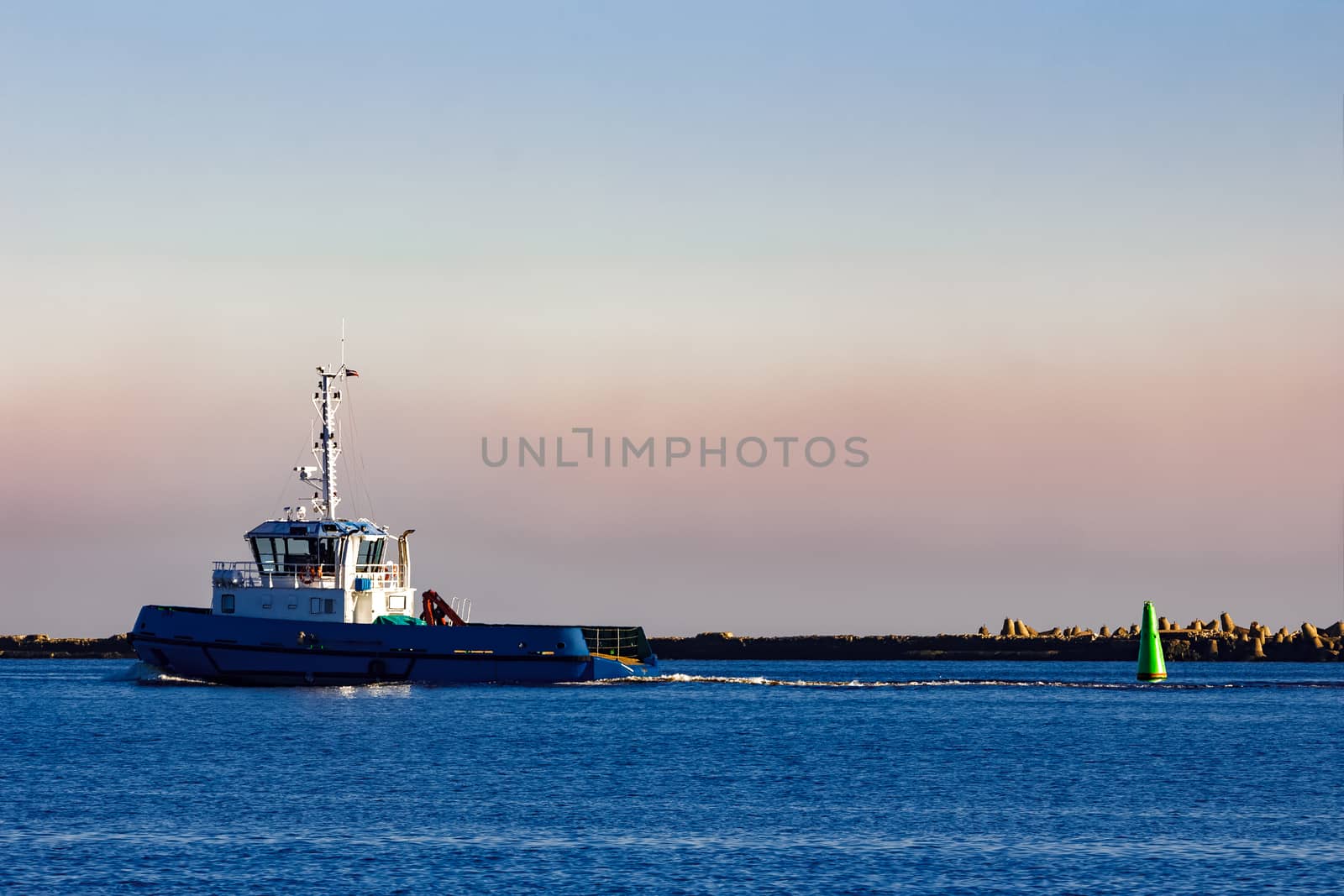 Blue small tug ship leaving Riga and entering the Baltic sea