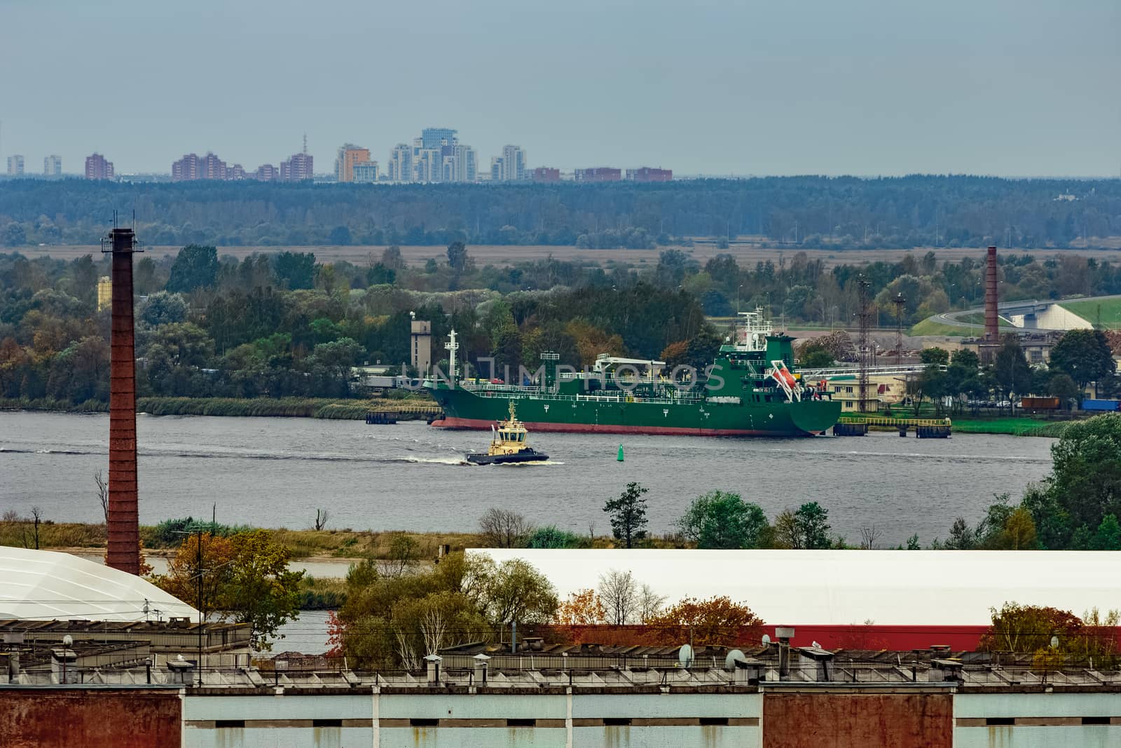 Tug ship moving past the cargo port at Riga city