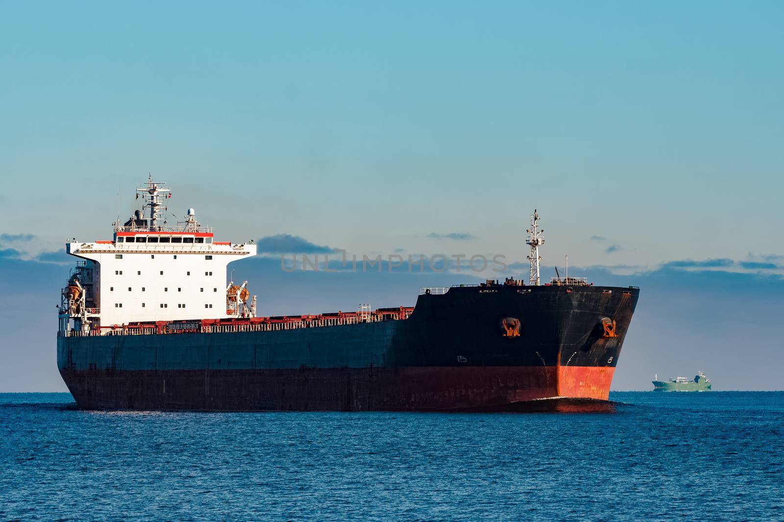 Black cargo ship moving in still Baltic sea water. Riga, Europe