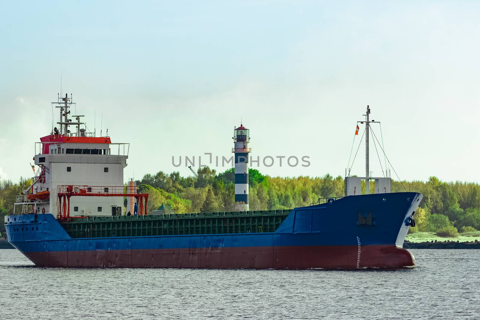 Blue cargo ship leaving the port of Riga at sunny day