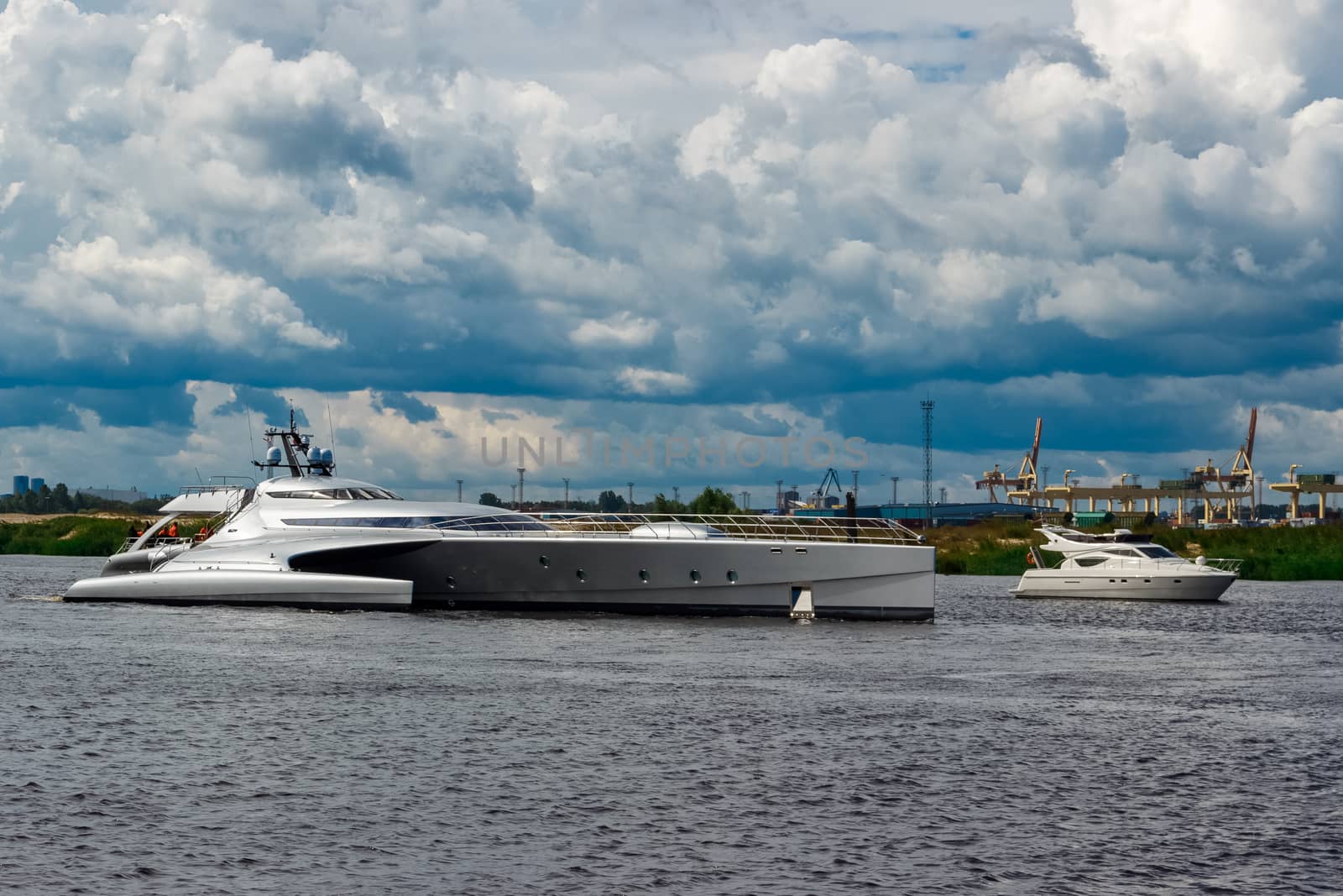 Large silver trimaran. Luxury yacht sailing by the river in Riga