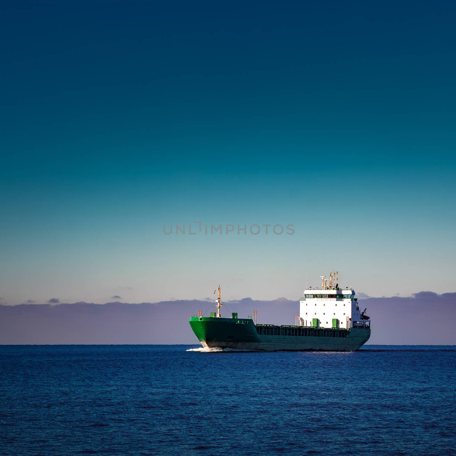 Green cargo ship moving in still water of Baltic sea