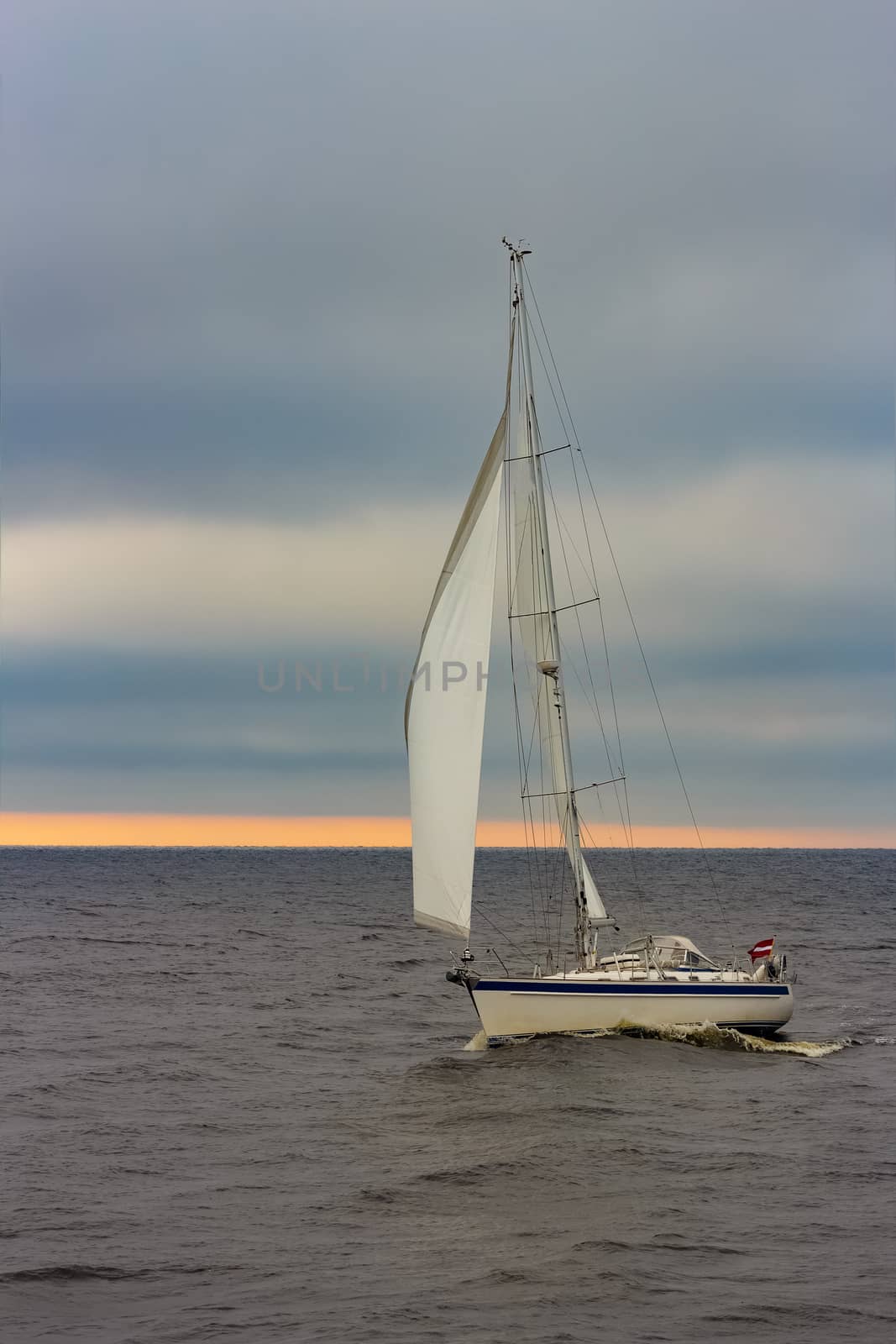 White sailboat traveling in Baltic sea in cloudy day