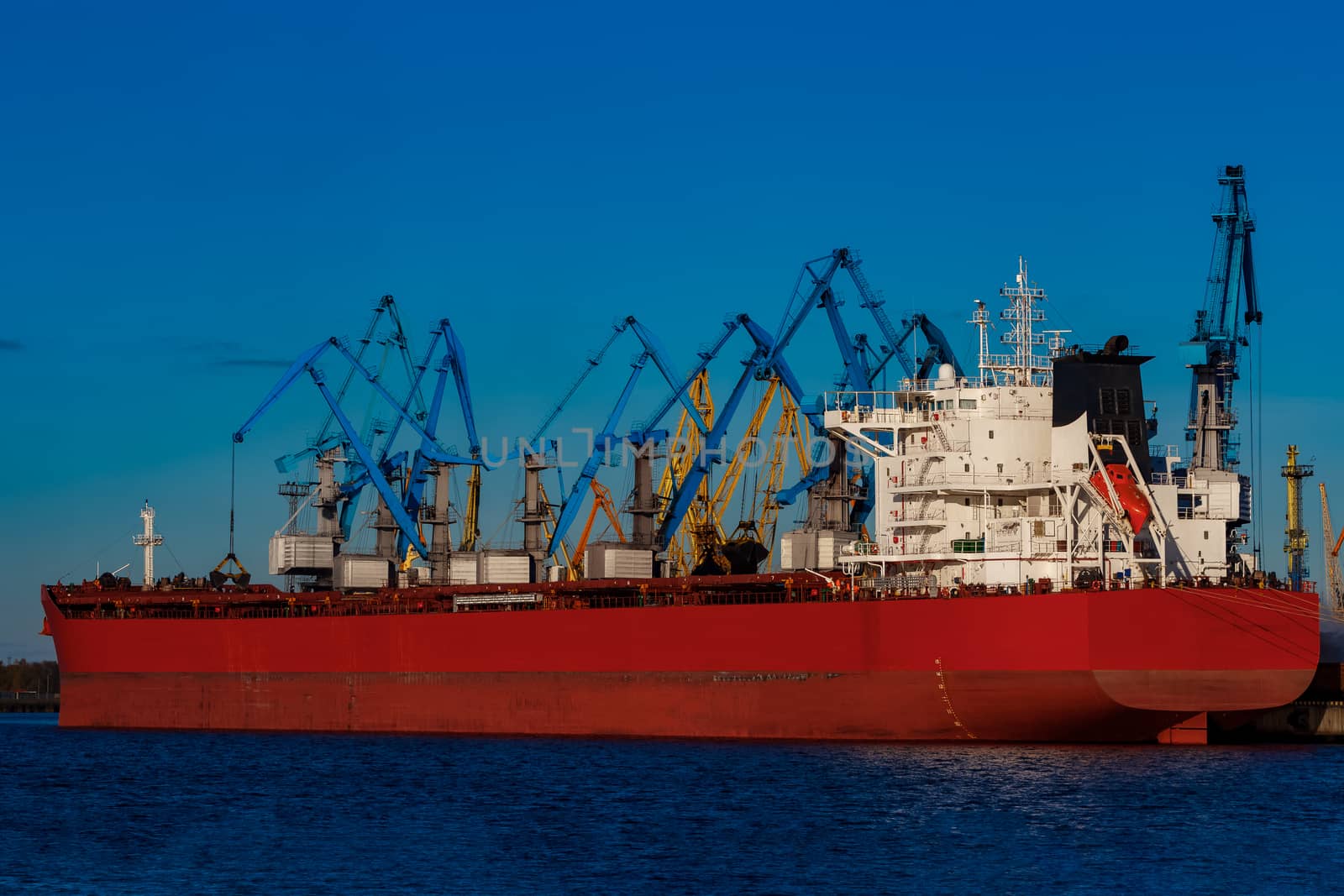 Red cargo ship loading in the port of Riga, Europe