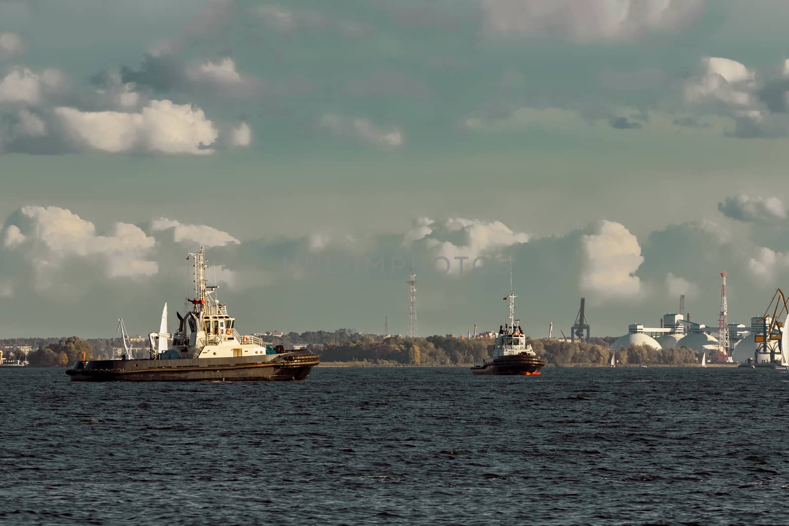 Two tug ships are accepting cargo vessel at Daugava river