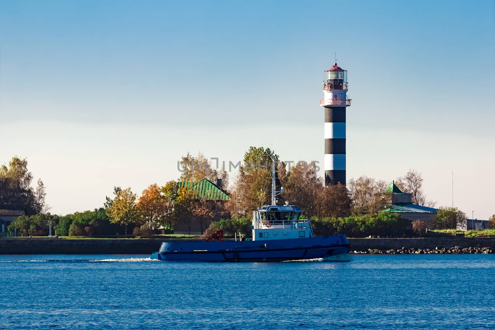 Blue small tug ship leaving Riga and entering the Baltic sea