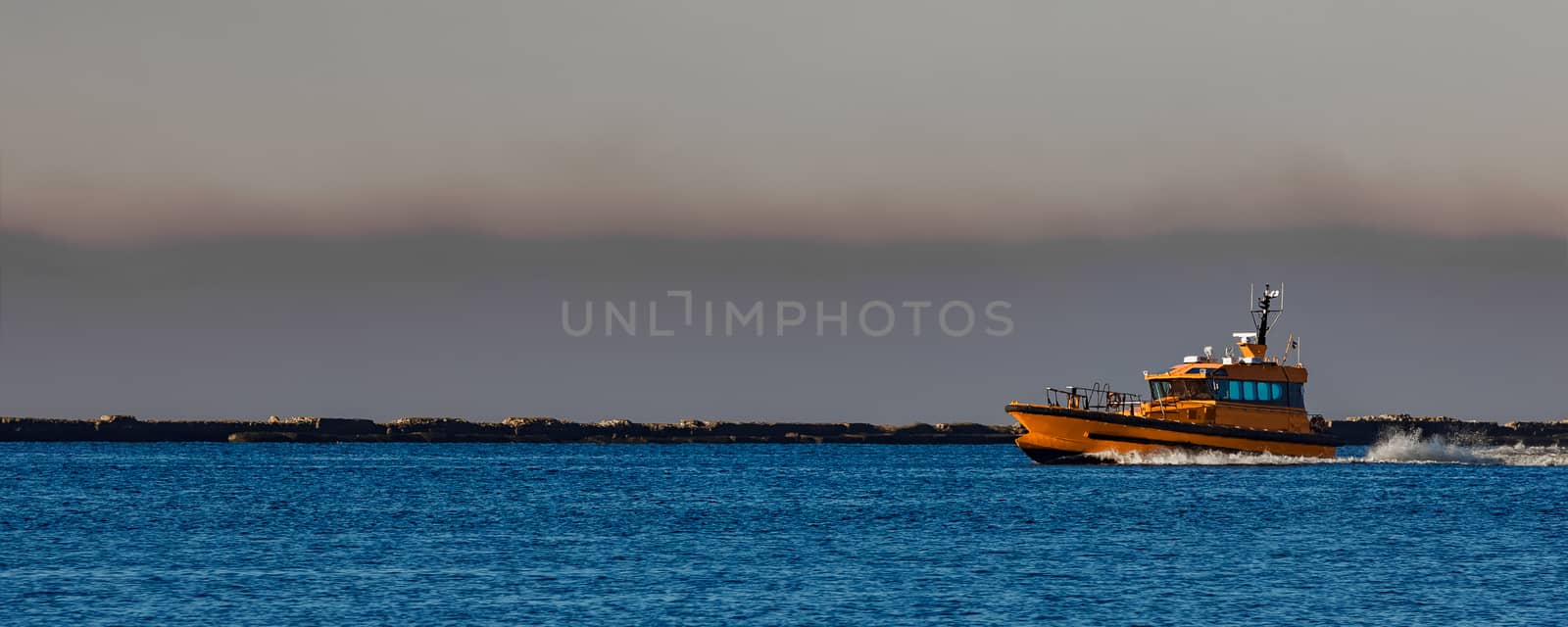 Orange pilot ship sailing from the Baltic sea in Latvia