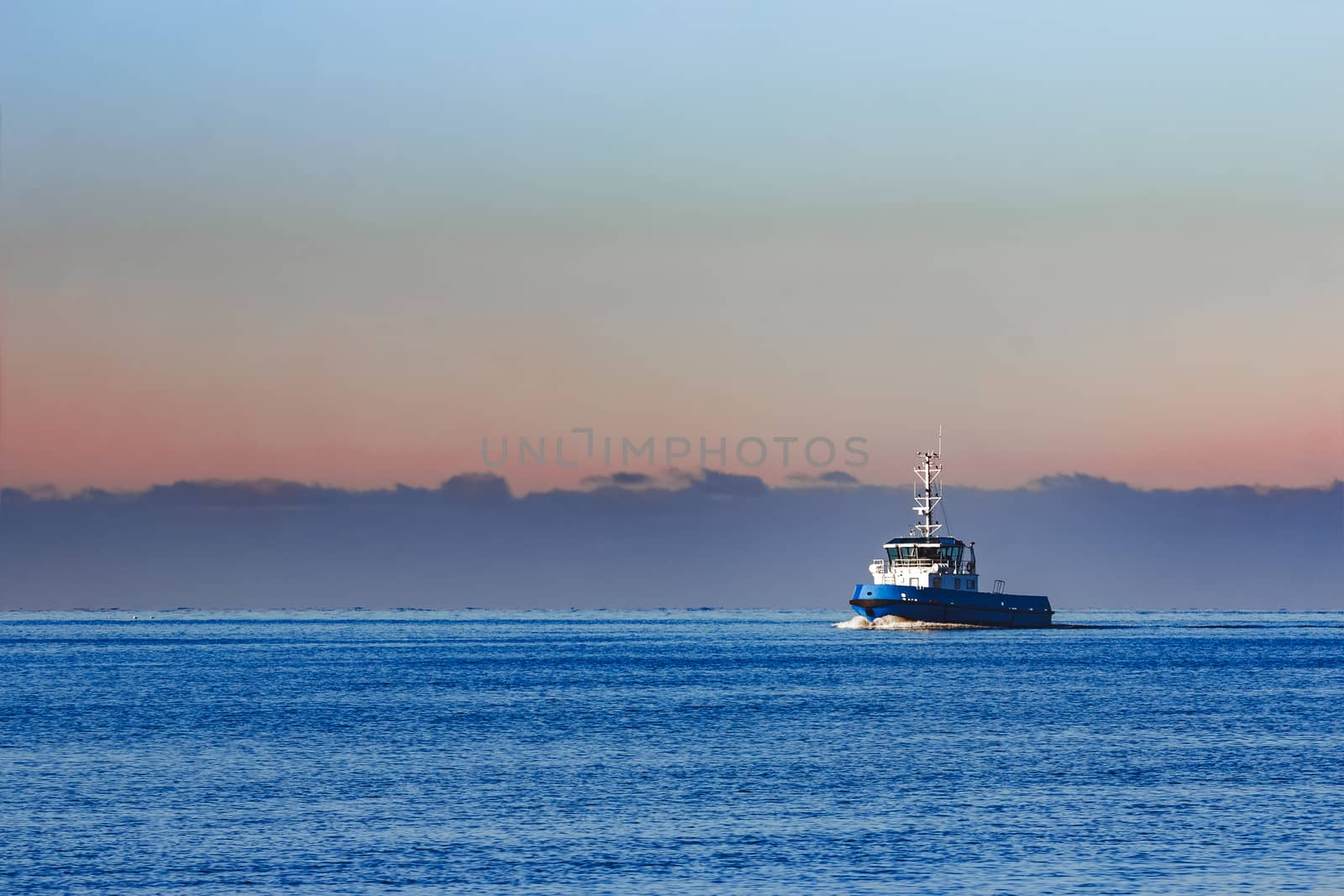 Blue small tug ship sailing from the Baltic sea in the morning