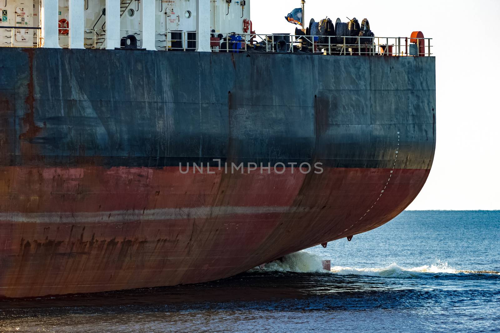 Black cargo ship's stern in still water close up. Riga, Europe