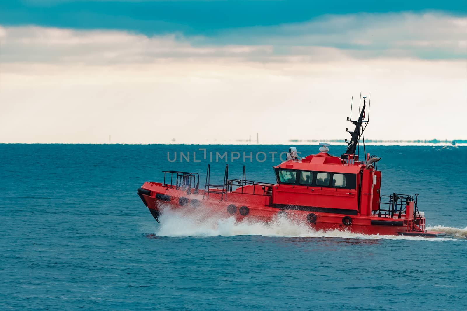 Red pilot ship sailing in still Baltic sea water