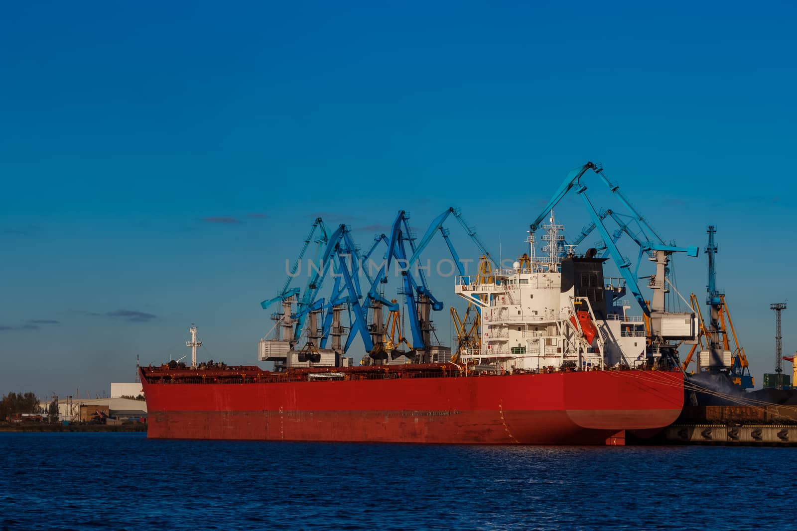 Red cargo ship loading in the port of Riga, Europe